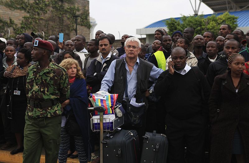 Pasajeros que no han podido coger sus vuelos esperan mientras continúan las labores de extinción en el Aeropuerto Internacional Jomo Kenyatta de Nairobi.