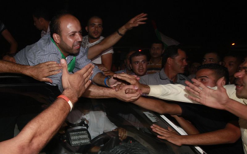 Uno de los presos palestinos liberados saluda a los cientos de personas que han acudido a su encuentro en el cruce de Erez, en Gaza