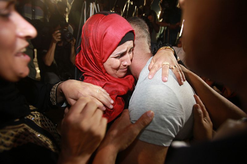 Dos palestinos se abrazan en el momento de la llegada de los presos palestinos liberados por Israel