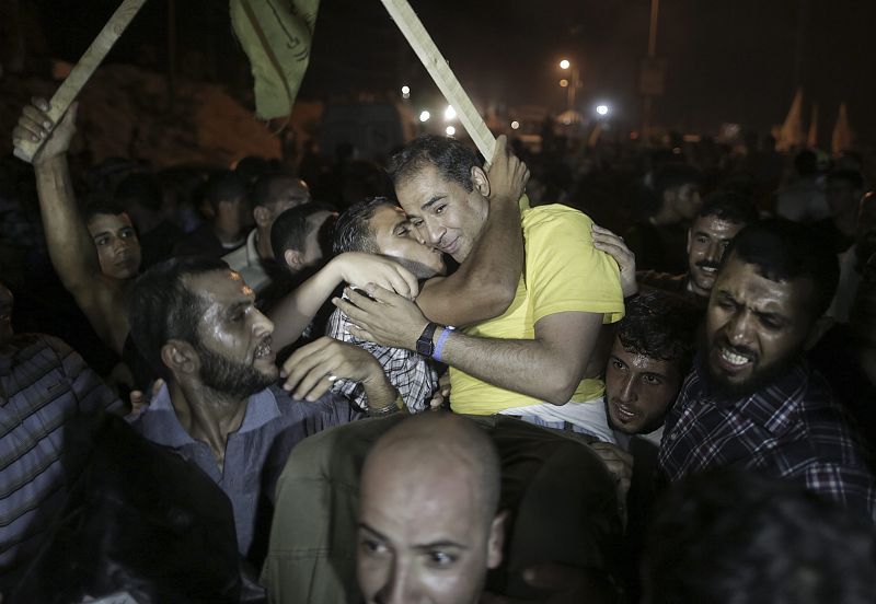 Dos palestinos se abrazan en la llegada a Gaza de quince de los veintiseis presos puestos en libertad por Israel