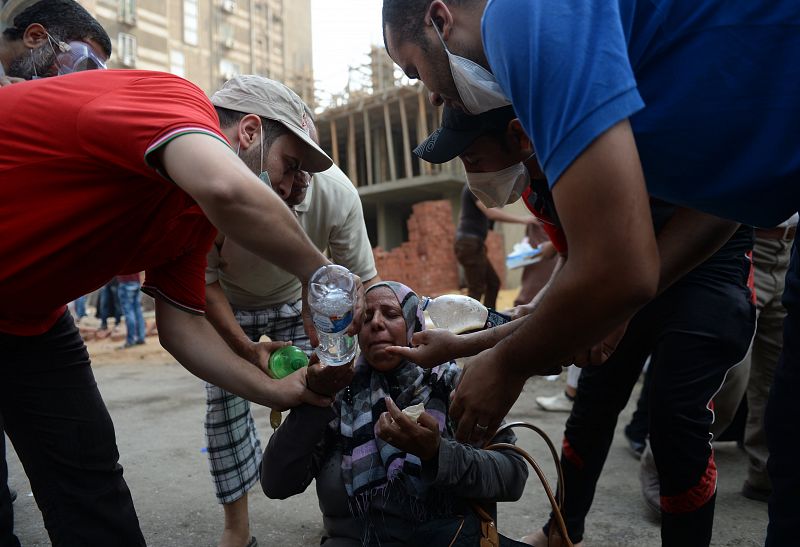 Un grupo de jóvenes ayudan a una mujer que acaba de inhalar gas lacrimógeno en las cercanías de la plaza de Rabaa Al Adauiya en El Cairo.