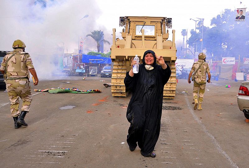 Una mujer corea consignas mientras las fuerzas de seguridad utilizan una pala excavadora para desmantelar uno de los dos asentamientos de los simpatizantes del depuesto presidente Mohamed Mursi en la plaza del Nahda, cerca de la Universidad de El Cai