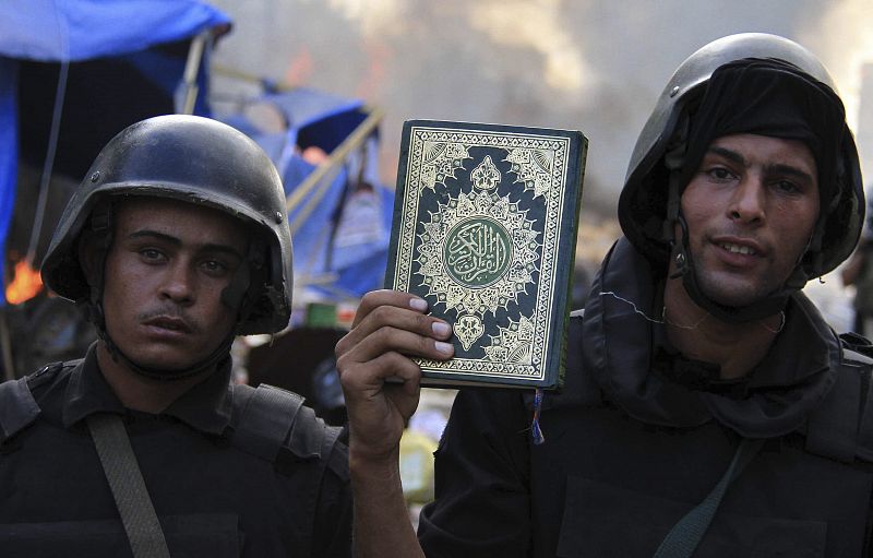 Un policía antidisturbios muestra un ejemplar del Corán encontrado en el asentamiento desalojado de la plaza Rabaa Adawiya.