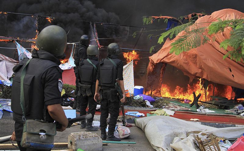 Miembros de la policia antidisturbios egipcia observan cómo arde un campamento de partidarios de Morsi en la plaza Rabaa Adawiya.