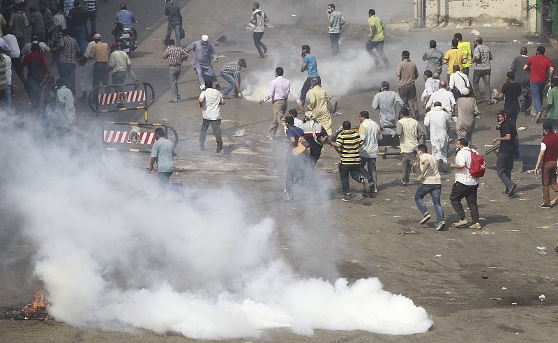 Partidarios de los Hermanos Musulmanes y del depuesto presidente Morsi huyen de los gases lacrimógenos lanzados por la policia egipcia en las inmediaciones de la Universidad de El Cairo.