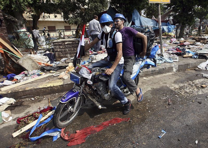 Varias personas intentan recuperar enseres entre las ruinas tras la expulsión de los manifestantes de la plaza Rabea al Adauiya en El Cairo