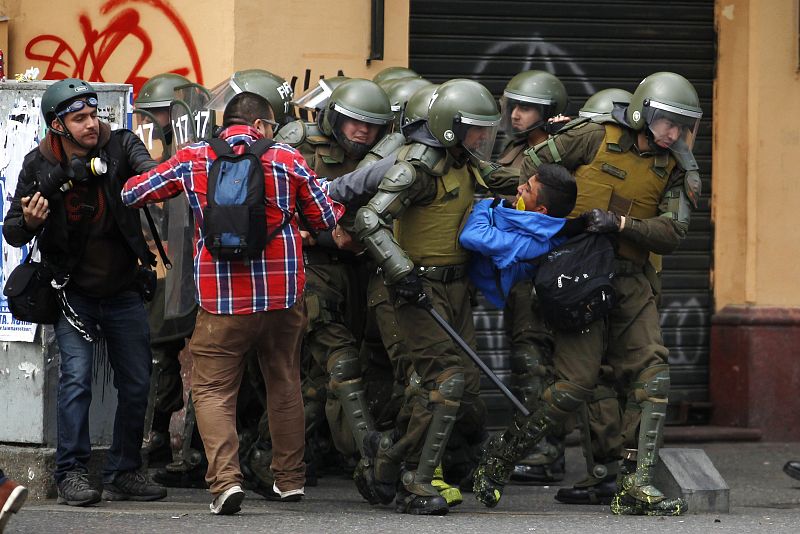 Los Carabineros forcejean y detienen a un manifestante. Al menos 52 estudiantes detenidos en la jornada de hoy son menores de edad.