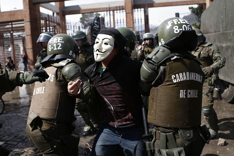 La Policía de Chile detiene a uno de los participantes en las protestas, con una máscara de Guy Fawkes, durante los disturbios posteriores a la concentración en memoria de los desaparecidos por el golpe de Estado que acabó con el Gobierno y la vida d