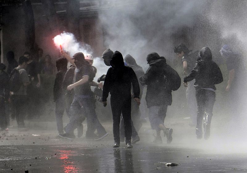 Un grupo de encapuchados enciende bengalas durante su enfrentamiento contra los antidisturbios chilenos en las protestas en conmemoración del golpe de Estado de Pinochet que acabó con el Gobierno y la vida de Salvador Allende en 1973