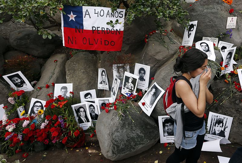 Una mujer se protege de los gases lacrimógenos junto al memorial de los detenidos desaparecidos durante las protestas en conmemoración del 40 aniversario del golpe militar de Pinochet al Gobierno socialista de Salvador Allende y su muert