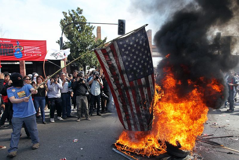 Un hombre quema una bandera de Estados Unidos durante los disturbios ocurridos tras una marcha en conmemoración del 40 aniversario del golpe militar de Augusto Pinochet.