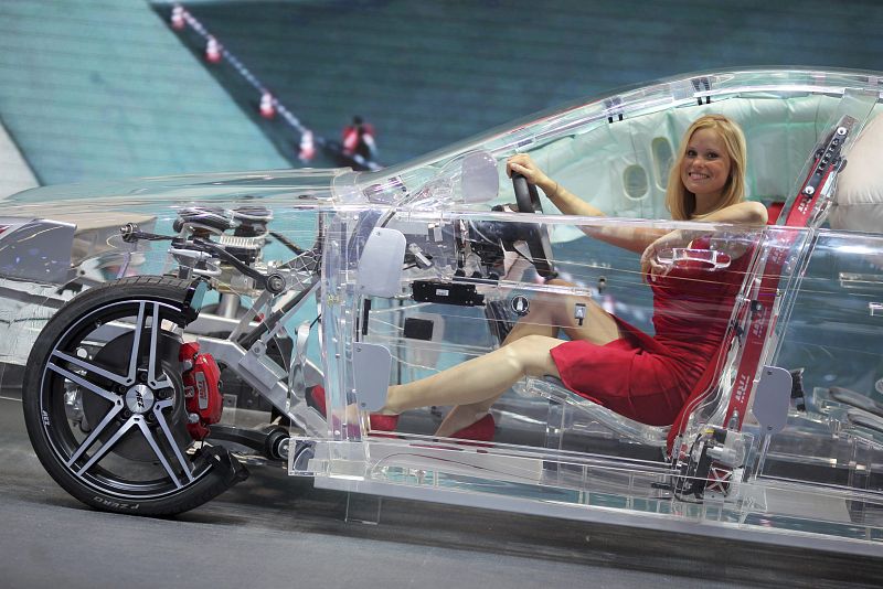 Una azafata posa en un modelo de vehículo acrílico durante la presentación de Thompson Ramo Wooldridge (TRW), un fabricante de piezas de coches