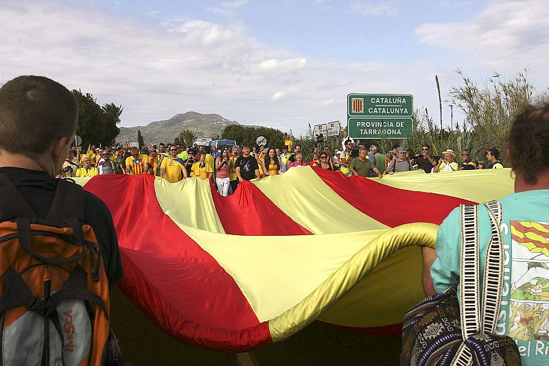 Varias personas despliegan una "senyera" en Alcanar.