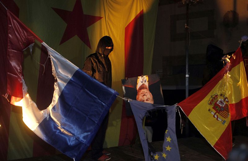 Encapuchados en un acto de la izquierda independentista queman las banderas de España, Francia y la Unión Europea, además de una foto del rey Juan Carlos, en Barcelona.