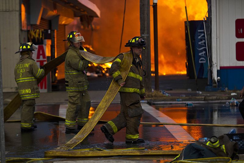 El cuerpo de bomberos de Nueva Jersey despliega las mangueras para tratar de sofocar el incendio desatado en el paseo costero de Seaside Park
