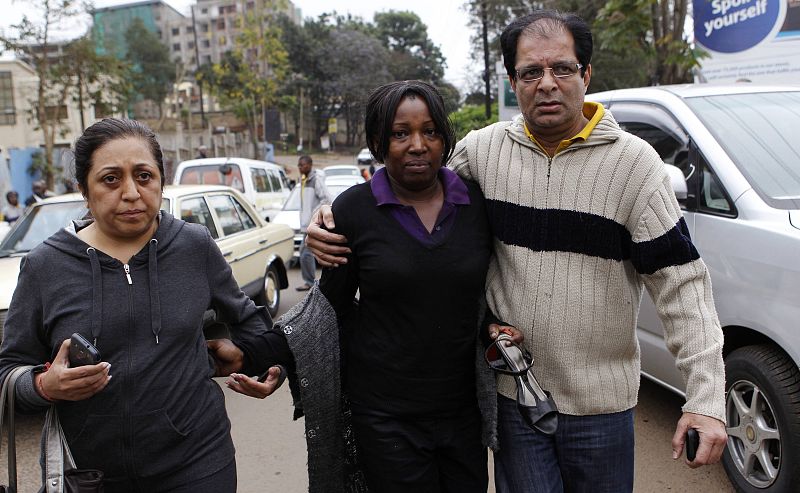 A woman is escorted after being evacuated as gunmen storm Westgate mall in Nairobi