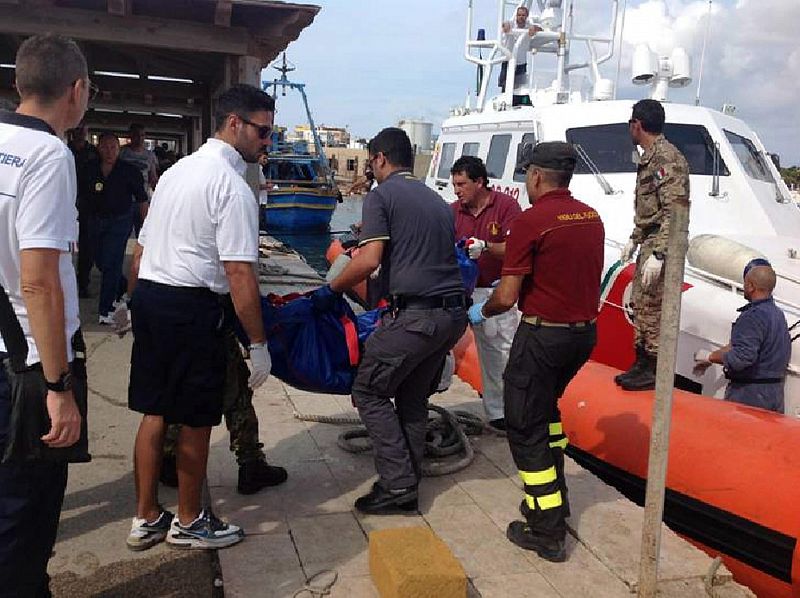 Miembros de los servicios de emergencia recuperan el cadáver de un inmigrante