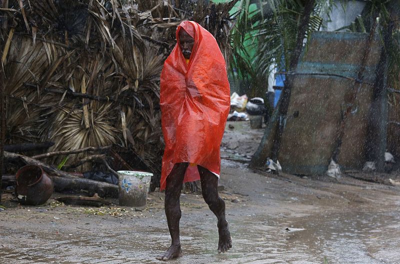 A man covers himself with a plastic sheet during heavy rain brought by Cyclone Phailin as he moves towards a safer place at the village Donkuru in Srikakulam district in Andhra Pradesh