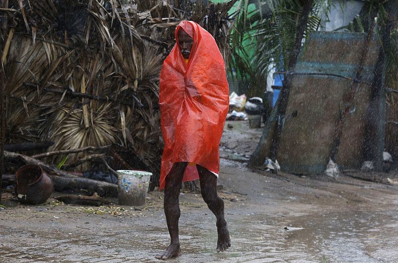 A man covers himself with a plastic sheet during heavy rain brought by Cyclone Phailin as he moves towards a safer place at the village Donkuru in Srikakulam district in Andhra Pradesh