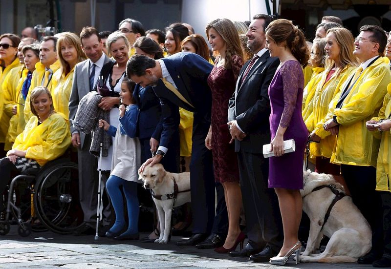 Príncipe Felipe acaricia al perro que acompaña a los miembros de la ONCE, entidad galardonada.