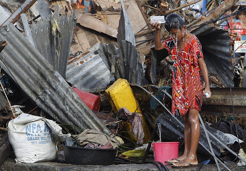 Un niño se baña con agua de una tubería rota en Tacloban. Las ONG han advertido que la contaminación del agua por restos orgánicos puede causar enfermedades.