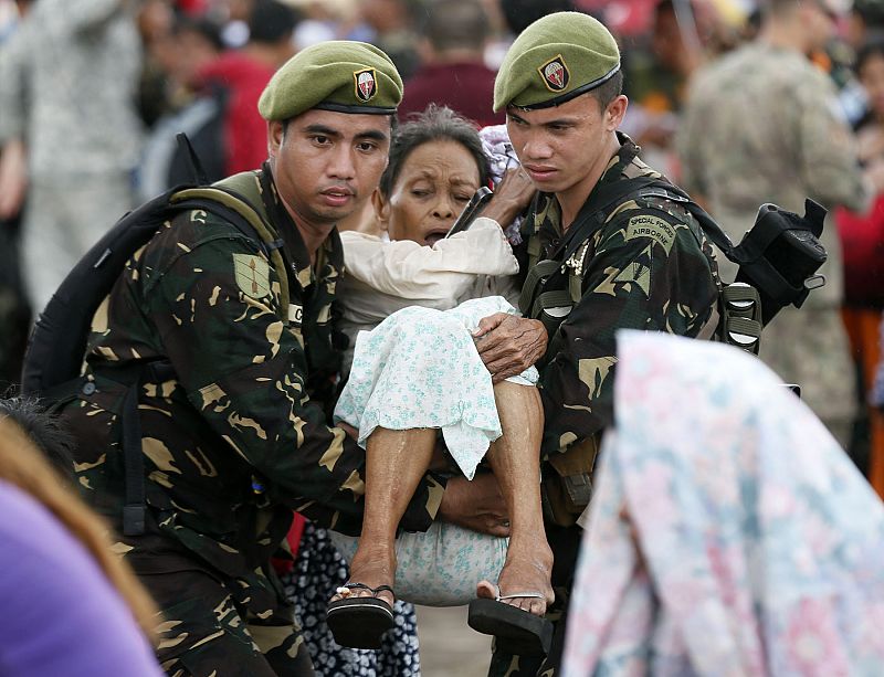Un soldado traslada a una mujer herida a uno de los aviones militares de EE.UU. que colaboran en la evacuación en Tacloban