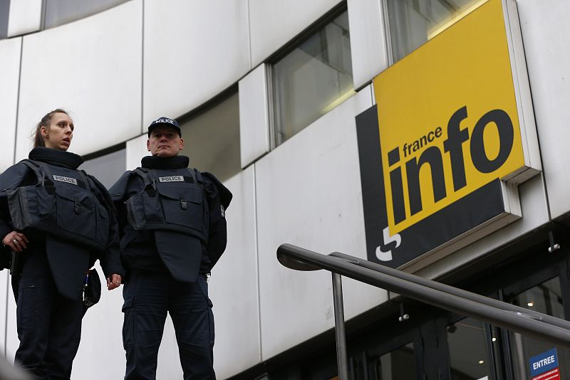 Dos agentes de policía vigilan el edificio de la Radio Nacional Francesa. La policía busca a un pistolero de 40 años, corpulento y con la cabeza rapada.
