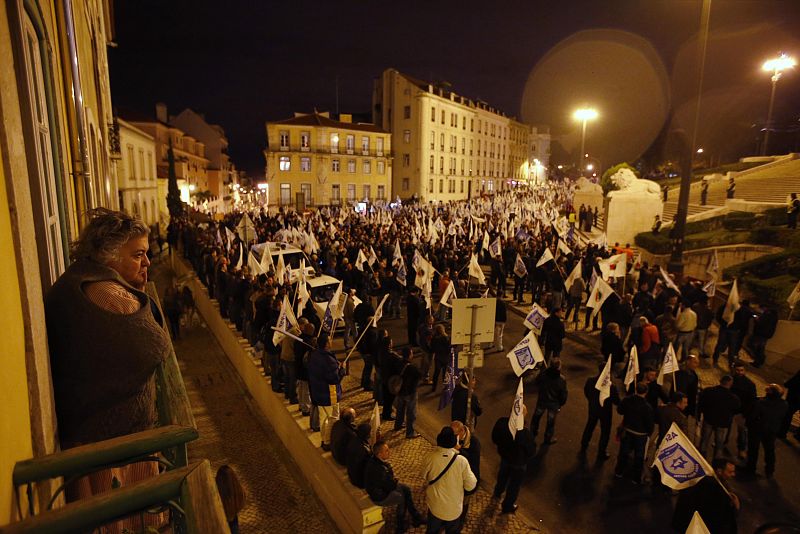 Una ciudadana observa las protestas anti-recortes de los cuerpos de seguridad de Portugal frente al Parlamento, en Lisboa