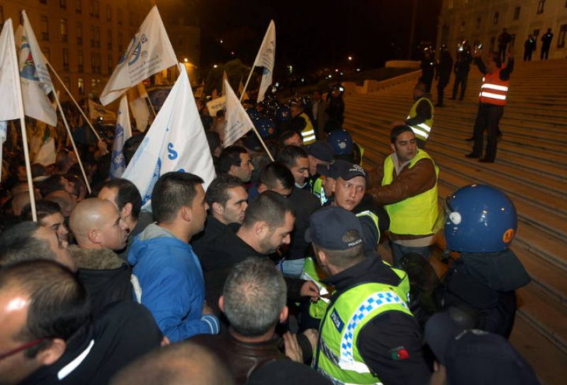 Manifestantes pertenecientes a las fuerzas de seguridad portuguesas tratan de superar al cordón policial frente al Parlamento en Lisboa (Portugal) en una protesta contra los recortes.