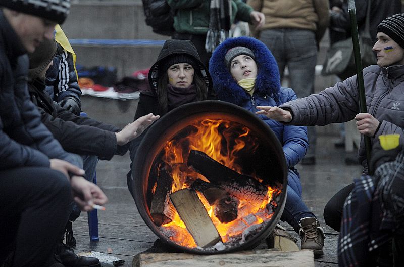 Varios manifestantes combaten el frío junto a una estufa tras pasar la noche en la Plaza de la Independencia de Kiev.