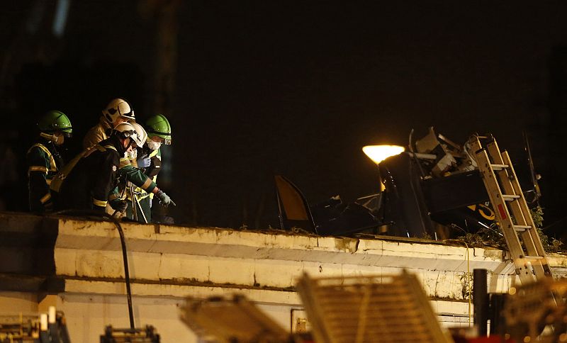 Miembros del equipo de rescate examinan la escena del accidente subidos al techo del bar Clutha Vaults, en Glasgow, donde se ha estrellado un helicóptero de la Policía