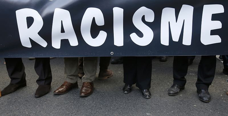 People hold a banner that reads, "Racism" as they attend a protest march called "The March for Equality and Against Racism" in Paris