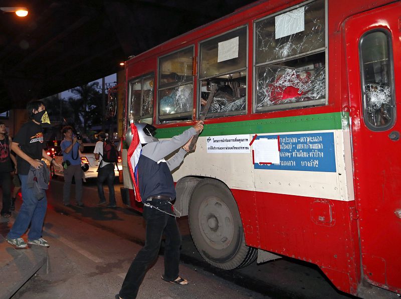 Un manifestante antigubernamental golpea las lunas de un autobús que transportaba a "camisas rojas", partidarios del Gobierno, a un estadio de Bangkok, Tailandia