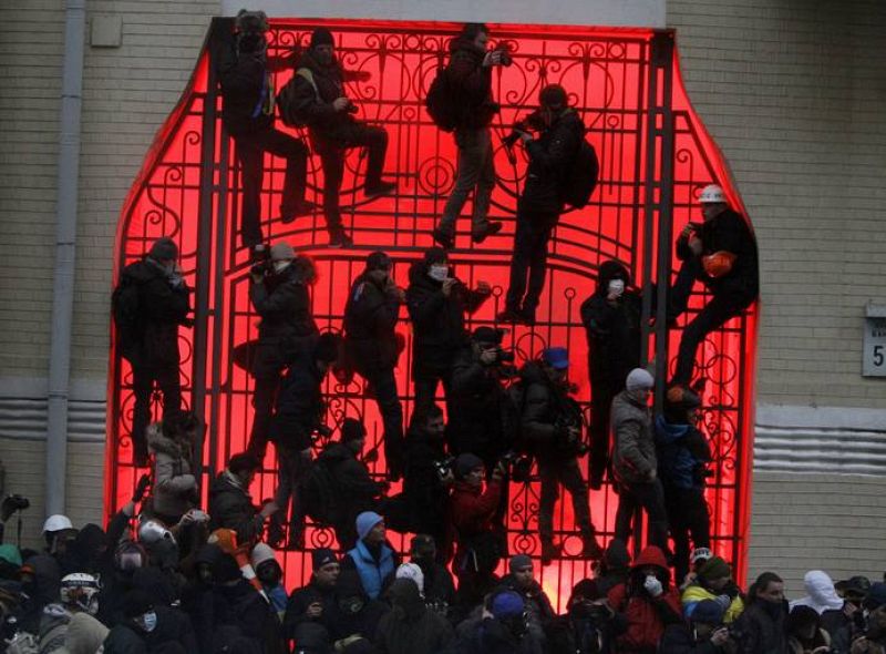 People climb up onto a gate near the presidential administration building during a rally held by supporters of EU integration in Kiev