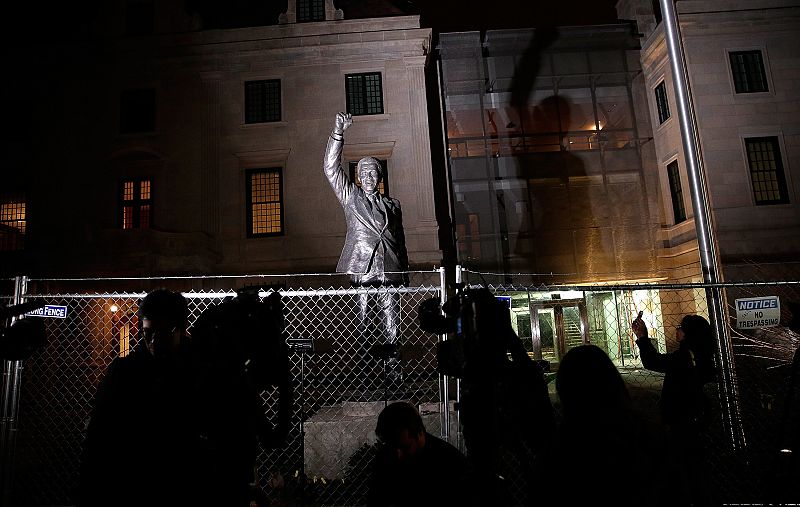 Periodistas y curiosos se concentran frente a la estatua de Nelson Mandela a las puertas de la embajada de Sudáfrica en Washington.