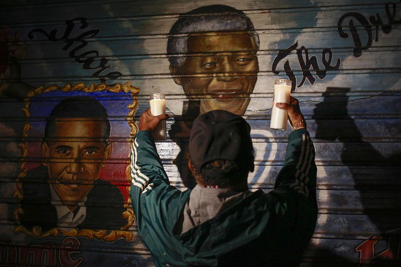 Un ciudadano sostiene dos velas en memoria del difunto presidente Nelson Mandela, ante un memorial instalado en Nueva York