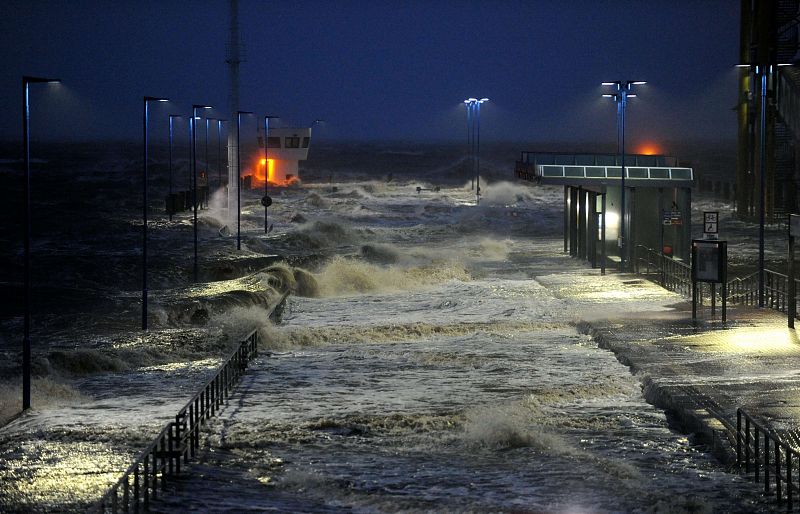 Las olas azotan el muelle de transbordadores en la costa del Mar del Norte en Dagebuell, Alemania