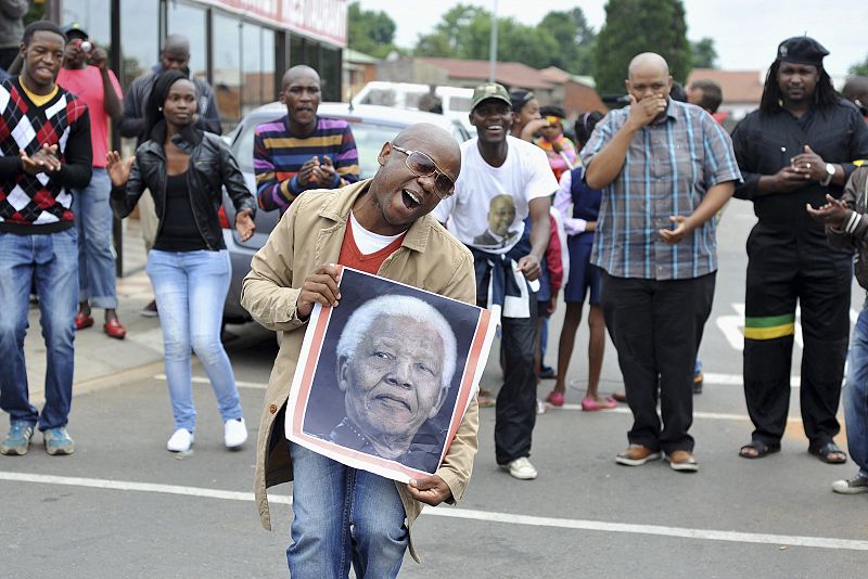 Un hombre en Sudáfrica porta una cartel con la foto de Mandela tras conocerse su muerte