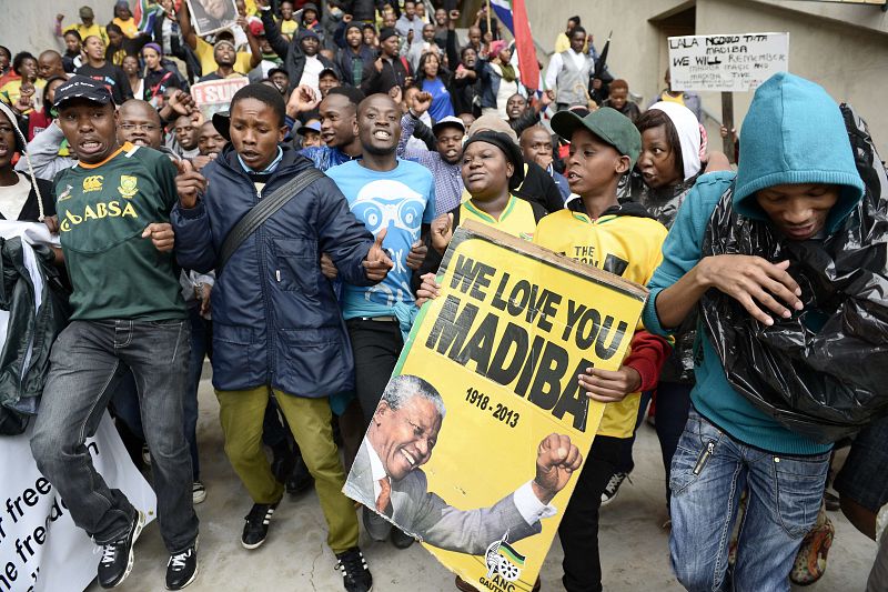 Un joven porta un cartel con una foto de Nelson Mandela