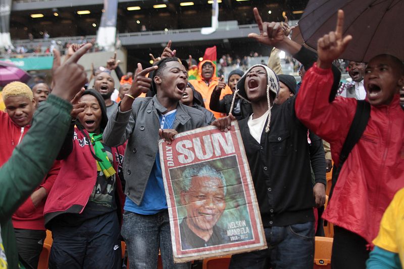 Una multitud de sudafricanos canta y baila bajo la lluvia antes del inicio del funeral de Nelson Mandela