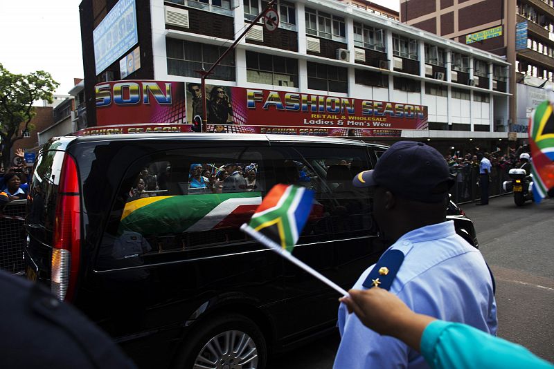 Banderas sudafricanas saludan el paso del féretro de Mandela por las calles. Las ceremonias terminarán el domingo con el entierro en su villa natal, Qunu