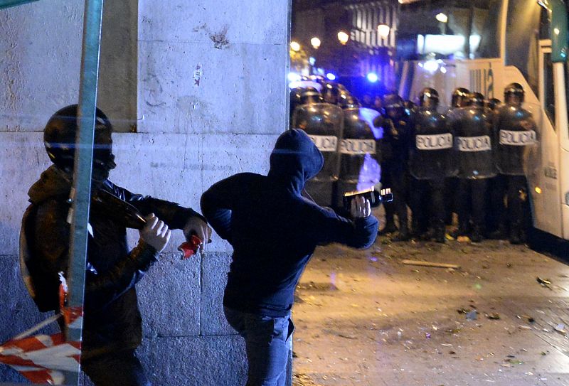 Dos manifestantes lanzan botellas a los antidisturbios durante los enfrentamientos ocurridos tras la movilización "Rodea el Congreso" en Madrid