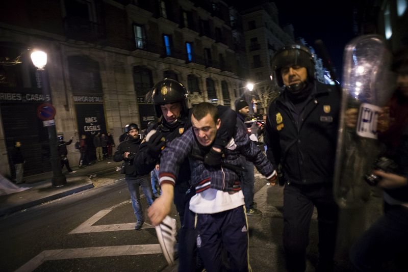 Dos policías detienen a un joven durante los incidentes registrados tras la concentración "Rodea el Congreso" que protesta contra la 'Ley mordaza'.