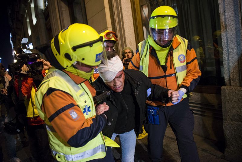 Dos miembros del Samur atienden a uno de los heridos durante los enfrentamientos entre manifestantes y antidisturbios tras la protesta "rodea el Congreso", en Madrid