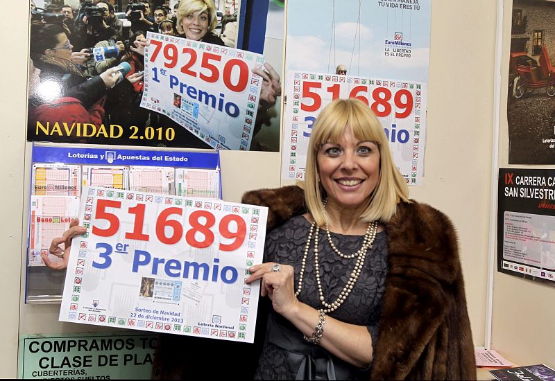 La propietaria de la administración de Lotería 22 de Zaragoza,Yolanda Delgado, muestra un cartel con el tercer premio del Sorteo de Navidad, el número 51.689.