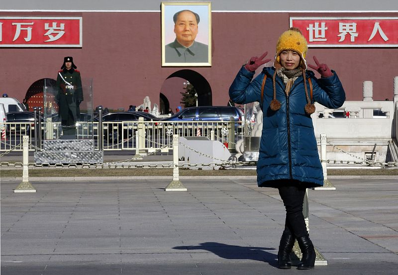 Una mujer posa delante del retrato del presidente chino Mao Zedong