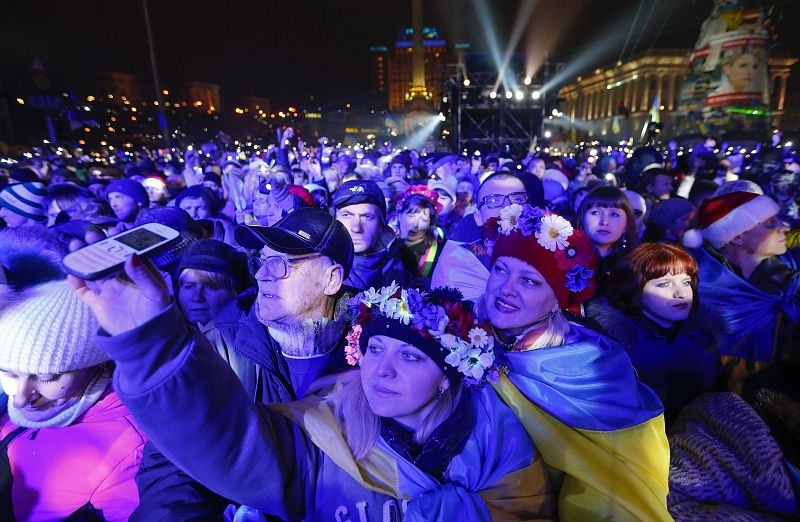 Varias personas sonríen reunidos en la plaza de la Independencia en Kiev (Ucrania) durante las celebraciones de Año Nuevo en Kiev