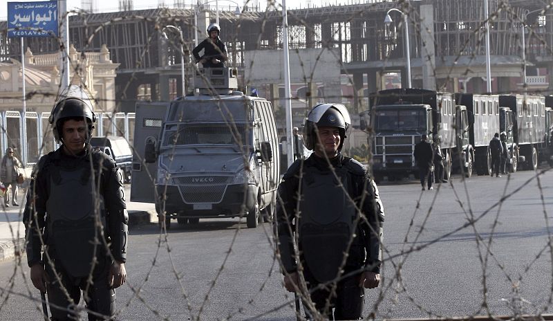 Policías antidisturbios egipcios permanecen tras una alambrada de espino durante la segunda sesión del juicio contra el expresidente egipcio Mohamed Morsi en la Academia Militar, en las afueras de El Cairo