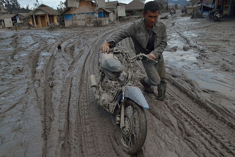 Un vecino de la población de Karo arrastra una motocicleta a través del barro y la ceniza