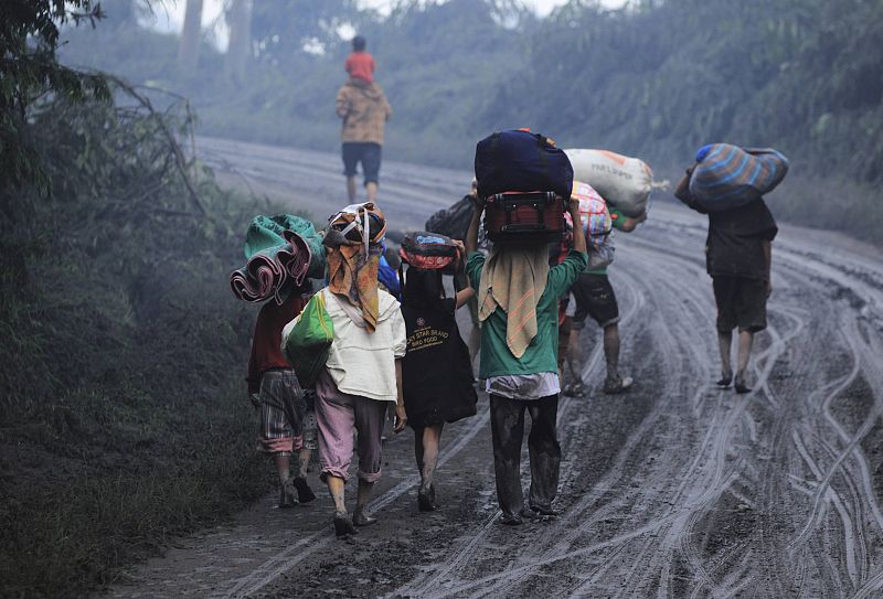 Habitantes de la población de Kuta Rakyat transportan sus pertenencias al ser evacuados entre la ceniza